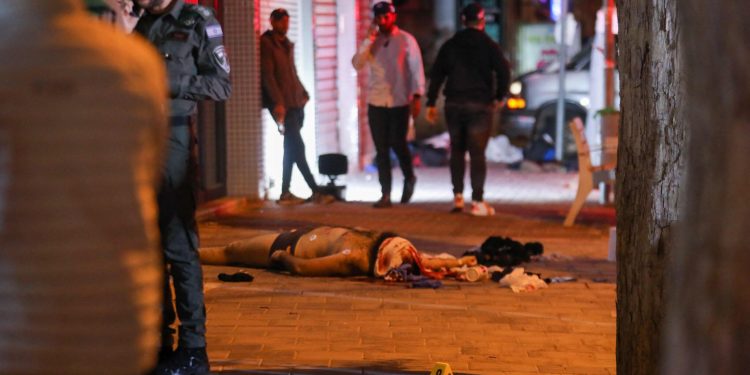 EDITORS NOTE: Graphic content / Israeli security forces gather next to the body of the assailant, after an attack that left two Israeli police dead, in the northern city of Hadera on March 27, 2022. The Magen David Adom emergency medical responders said that "two Israelis" were killed in the attack, with four other people taken to hospital and two more treated at the site. As Sunday's attack took place, Foreign Minister Yair Lapid was hosting his counterparts from three Arab states that recently normalised ties with Israel, alongside Egypt's top diplomat and the US secretary of state, at a resort in southern Israel, in a gathering that Israel called "historic". (Photo by GIL COHEN-MAGEN / AFP)