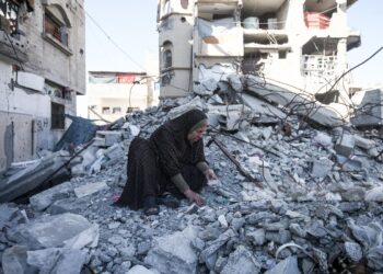 أم فلسطينية تنبش أنقاض منزلها في مخيم البريج بحثًا عن رفات أبنائها الأربعة