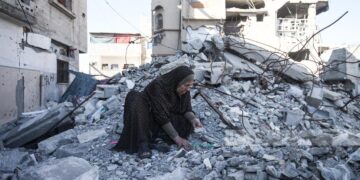 أم فلسطينية تنبش أنقاض منزلها في مخيم البريج بحثًا عن رفات أبنائها الأربعة